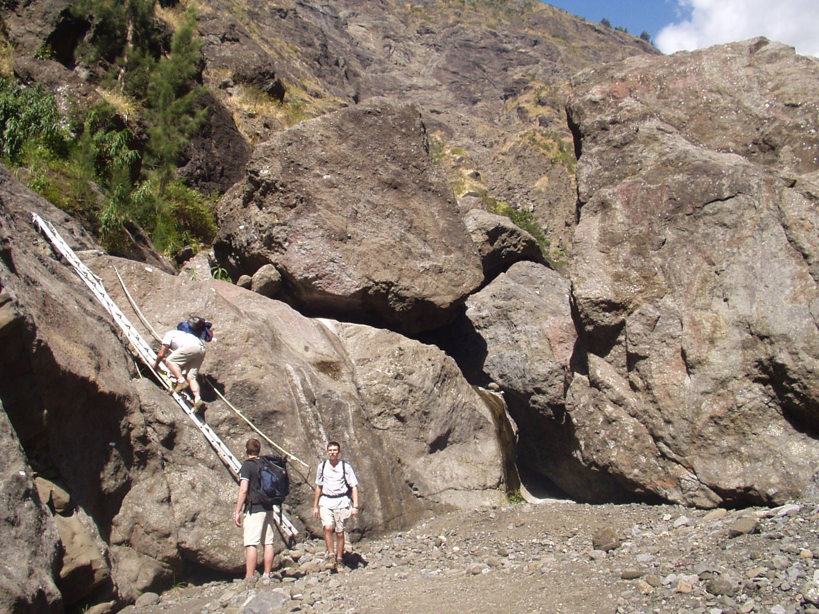 Des randonneurs gravissent une échelle métallique fixée dans de gros rochers