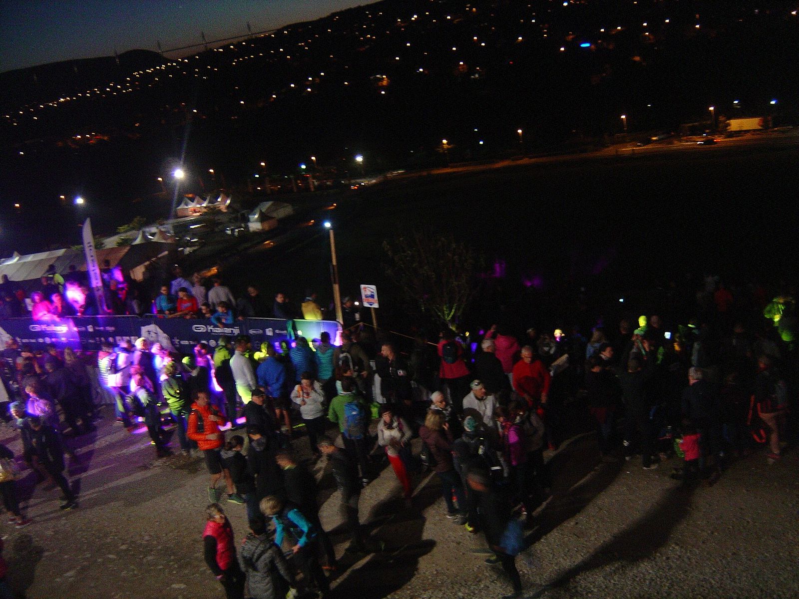 Foule de coureurs frontales allumées sur l'aire de Saint-Estève, avec Millau éclairée en contrebas