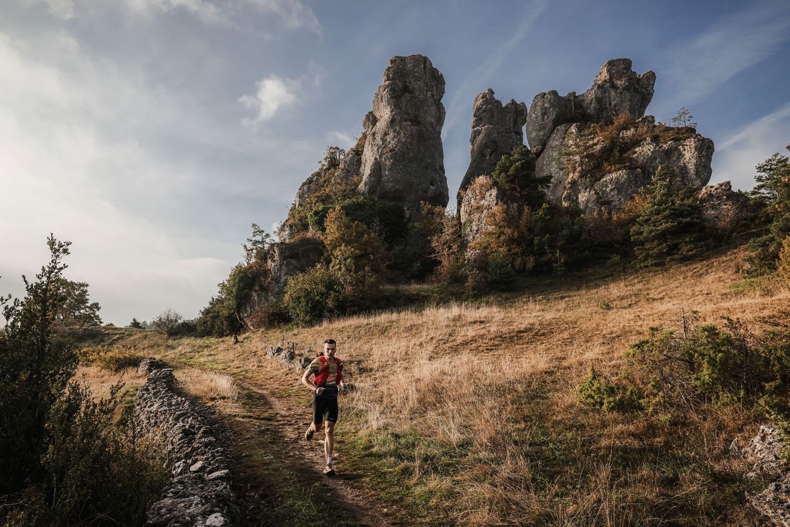 Un coureur seul sur un sentier herbeux au pied de grandes tours rocheuses